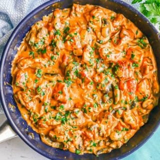 Overhead angle of creamy chicken paprikash in a large skillet with mushrooms and onions mixed in and fresh parsley sprinkled on top