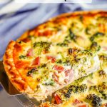 A pie server lifting up a piece of ham, cheddar and broccoli quiche from a baked pie dish with a text overlay on the photo