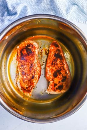 Two seared chicken breasts in an Instant Pot insert