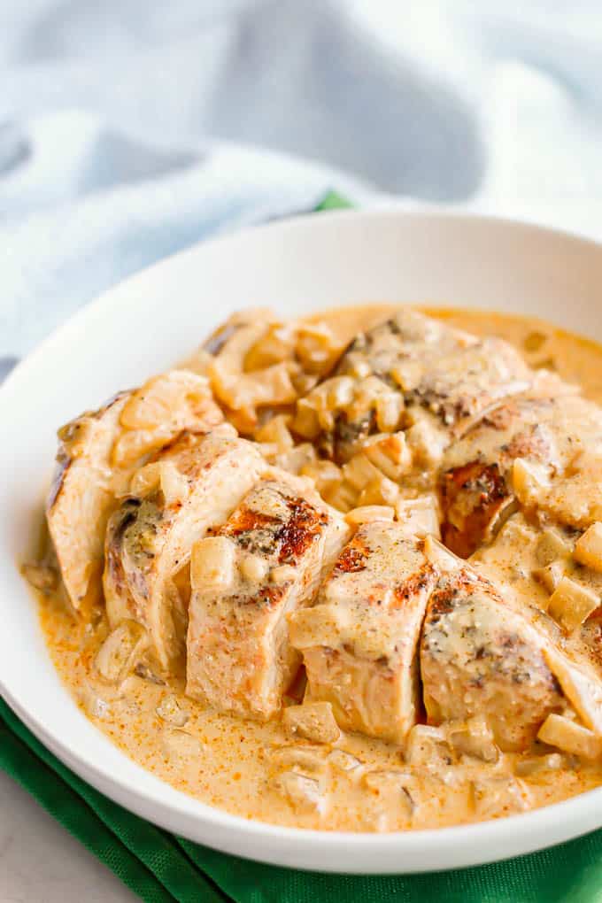Seasoned and seared chicken breasts sliced and served in a bowl with a creamy honey mustard sauce