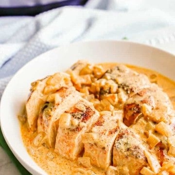 A low white serving bowl with sliced seasoned chicken breasts in a honey mustard sauce