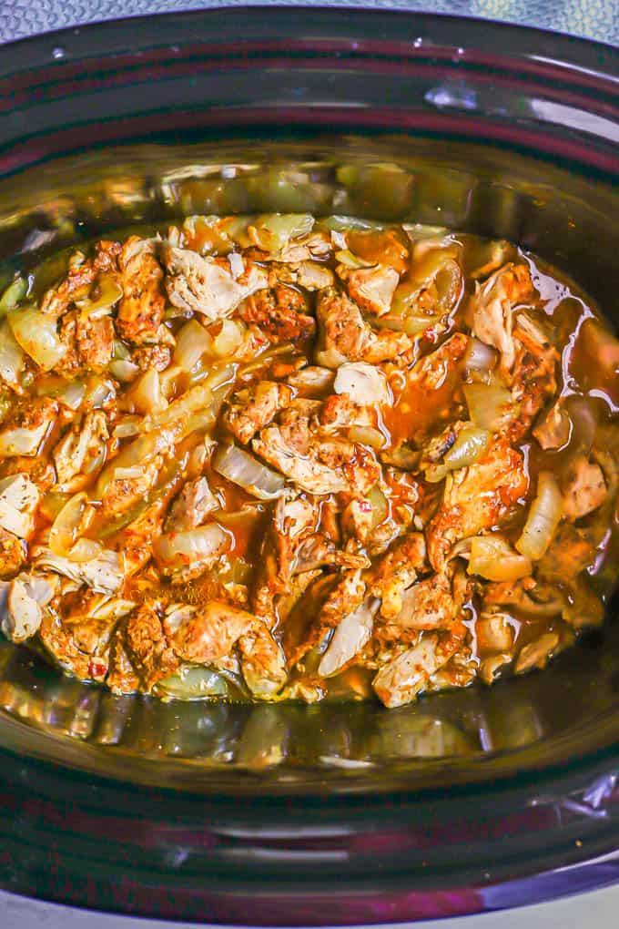 Slow cooker chicken shawarma after being cooked and chopped, then mixed with onions and the cooking liquid
