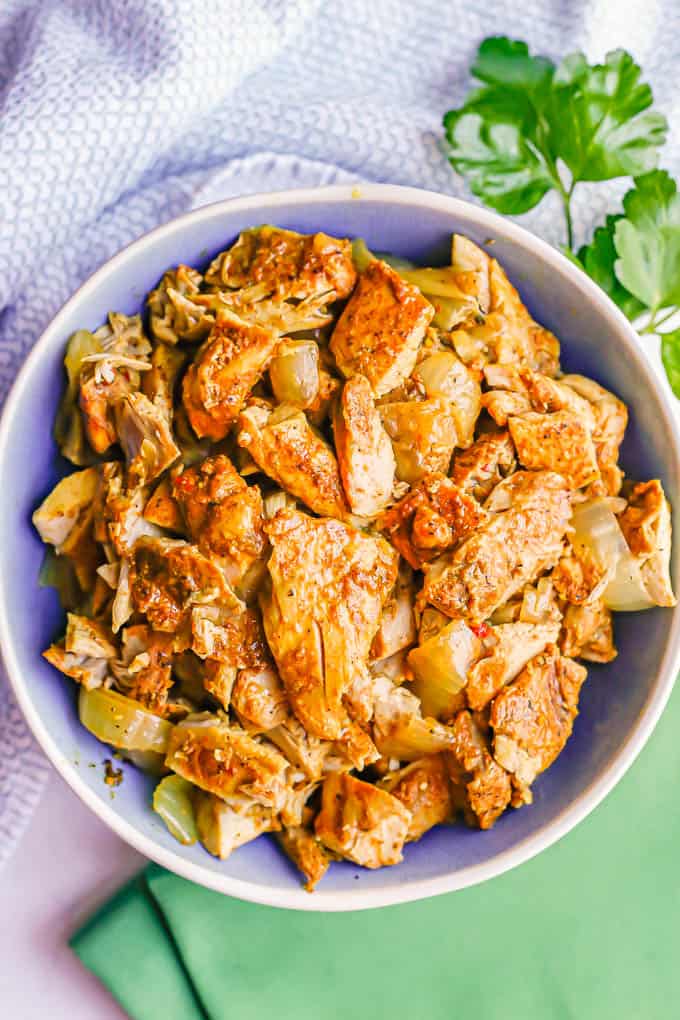 Chicken shawarma strips in a blue and white serving bowl with sprigs of parsley nearby