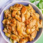 Chicken shawarma strips in a blue and white serving bowl with sprigs of parsley nearby and a text overlay on the photo