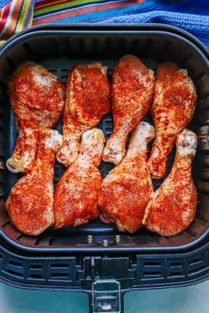 Seasoned chicken legs arranged in an Air Fryer before being cooked