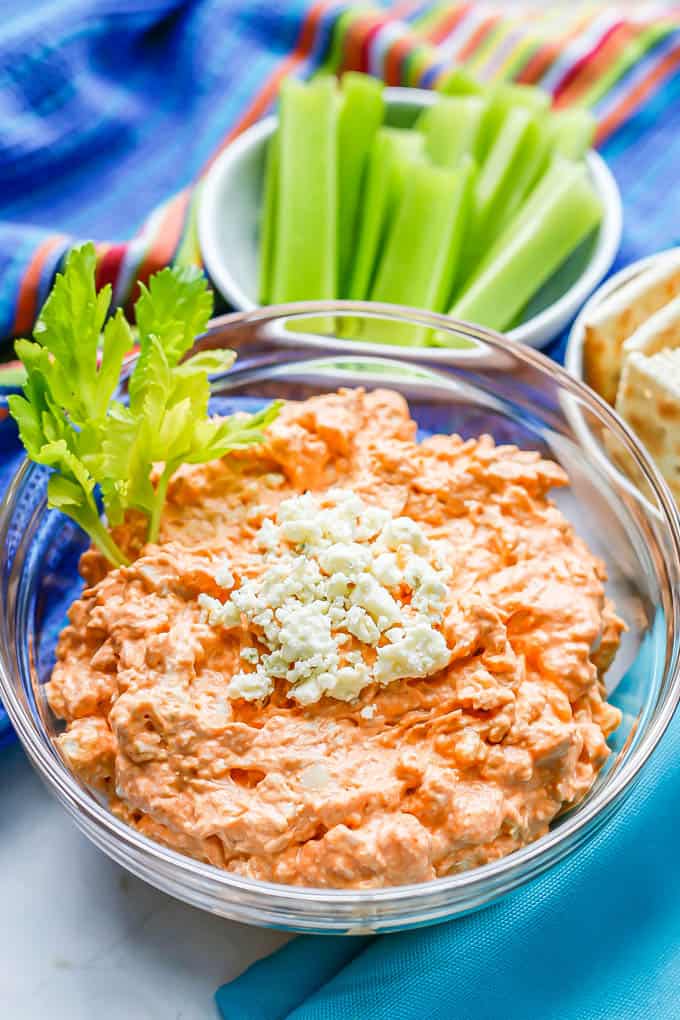 A creamy hot sauce chicken dip served in a glass bowl with blue cheese crumbles on top