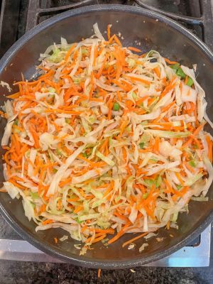 Slightly wilted shredded cabbage and carrots in a large skillet