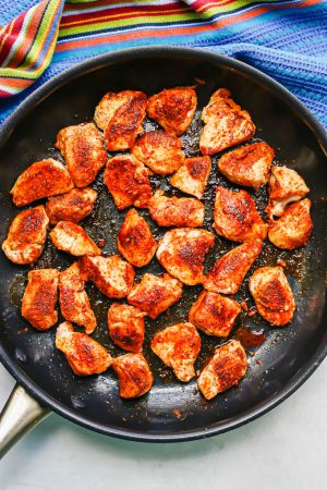 Cubed chicken with seasonings seared in a large skillet