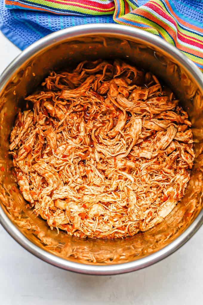Cooked and shredded chicken tacos mixture in an Instant Pot insert