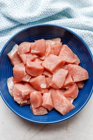 Cubed pieces of pork cutlet in a blue bowl before being seasoned and cooked