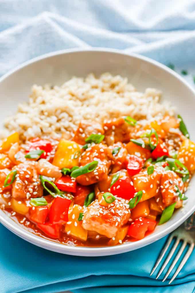 A low white bowl with steamed rice and sweet and sour pork