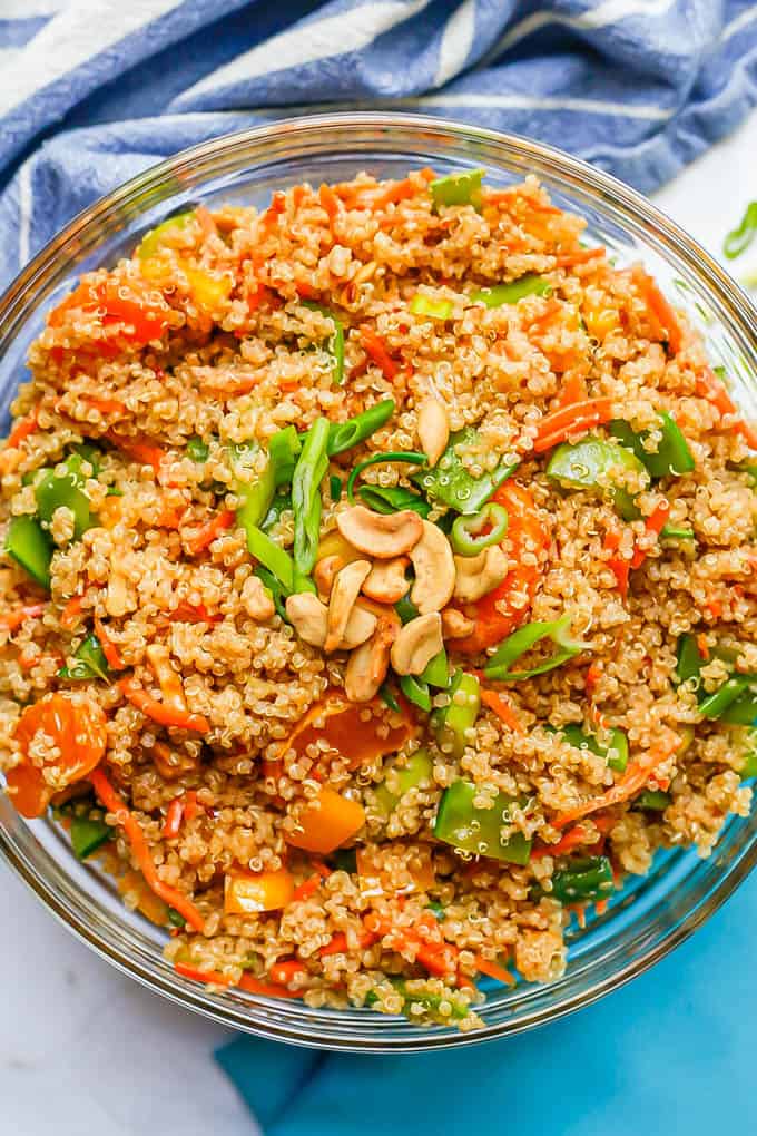 A vegetarian Asian quinoa salad with peppers, snow peas, mandarin oranges and cashews in a large glass bowl