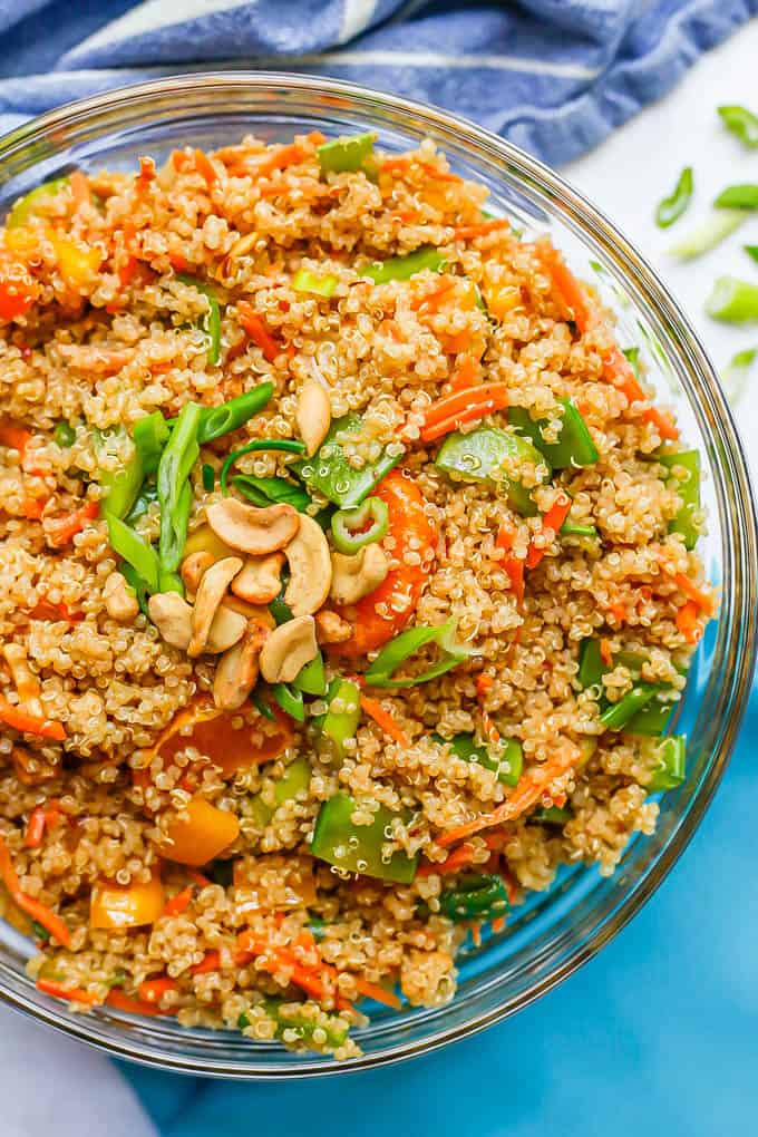 A crunchy quinoa salad with fresh veggies and cashews in a large glass bowl