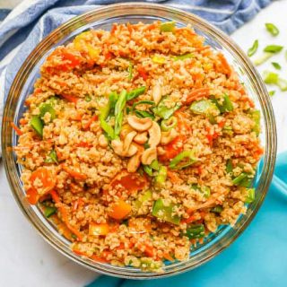 An Asian quinoa salad served in a large glass bowl with green onions on top and to the side