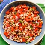 A marinated black eyed pea salad with vegetables in a blue bowl with a text overlay on the photo
