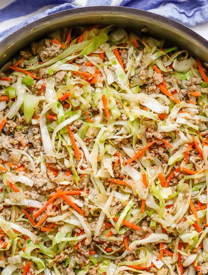 A large deep skillet with an egg roll mixture with ground turkey, cabbage and carrots