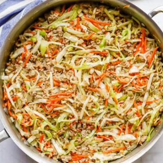 A large deep skillet with a mixture of ground turkey, shredded cabbage and shredded carrots