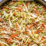 A large deep skillet with an egg roll mixture with ground turkey, cabbage and carrots and a text overlay on the photo