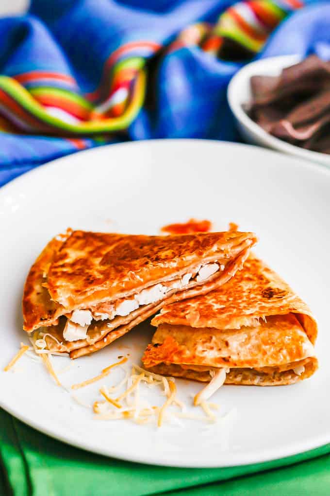 A seared and browned folded tortilla with cheese, chicken, refried beans and salsa