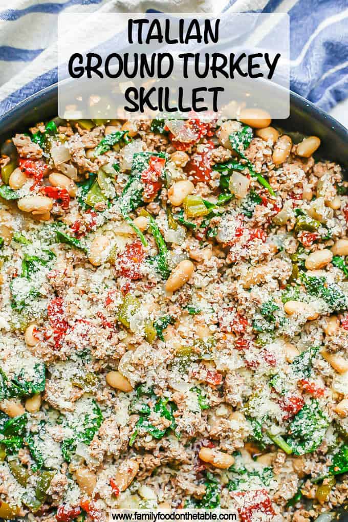 A skillet full of ground turkey, white beans, tomatoes and spinach with Parmesan cheese on top and a text overlay on the photo
