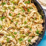 A large skillet with moo shu chicken with cabbage, mushrooms, egg and green onion on top with a plate of tortillas to the side and a text overlay on the photo