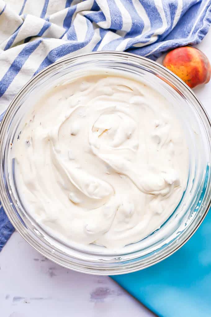 A large glass bowl with homemade no churn peach cream after being mixed together