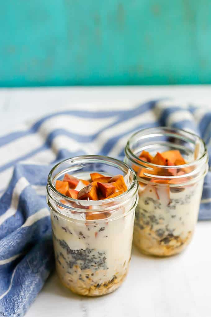 Peach overnight oatmeal in glass jars before being stirred together and refrigerated to set up