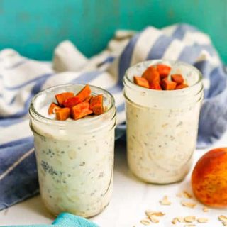 Two jars of overnight breakfast oats with peaches and a blue striped towel in the background