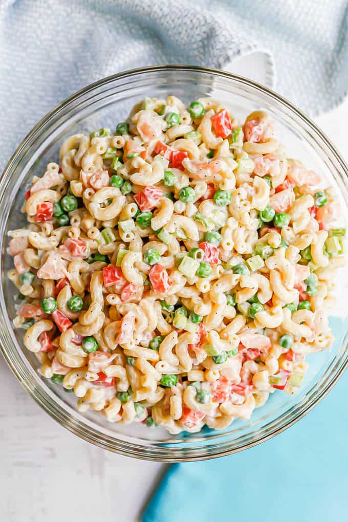 Shrimp pasta salad with peas, celery and red bell pepper in a large glass bowl