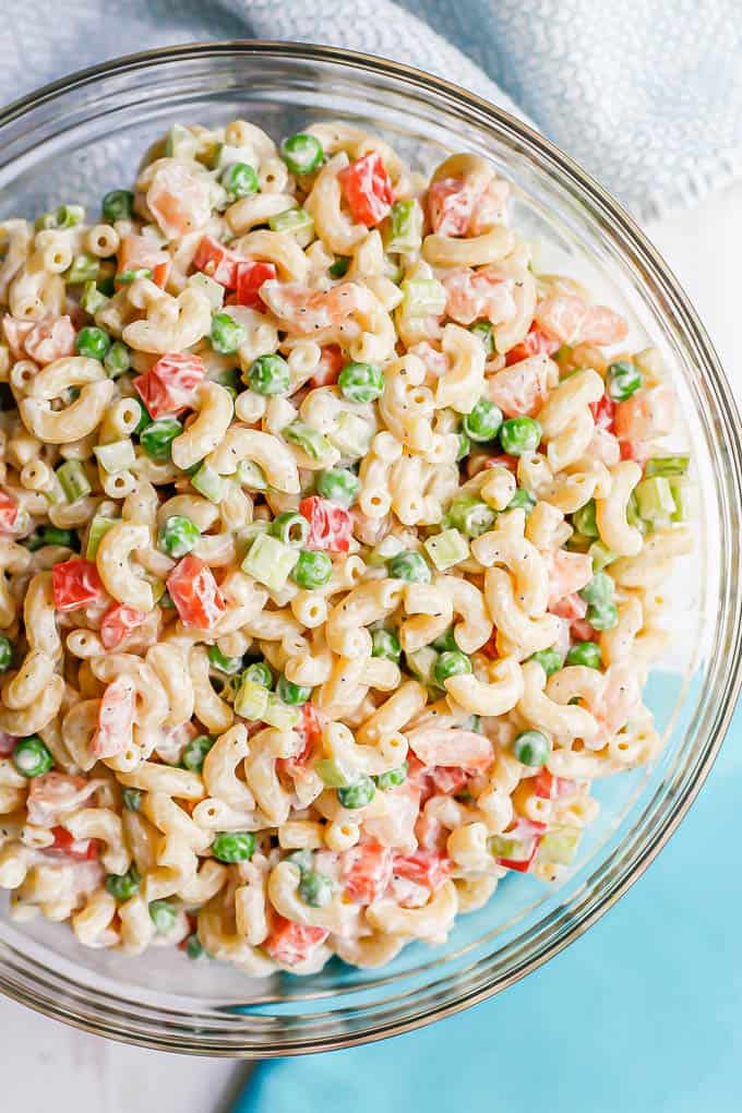 A large glass bowl with a picnic pasta salad with shrimp and peas