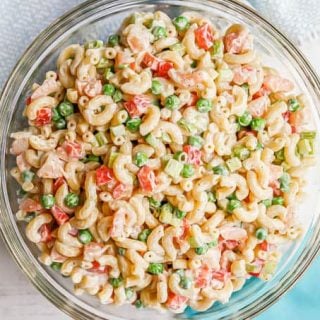 A cold shrimp pasta salad with peas and peppers served in a large glass bowl