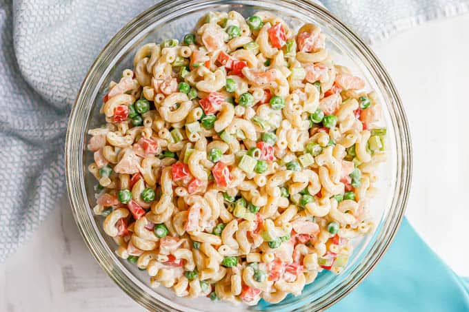 A cold shrimp pasta salad with peas and peppers served in a large glass bowl