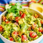 Avocado salad with tomatoes in a large white bowl with a text overlay on the photo
