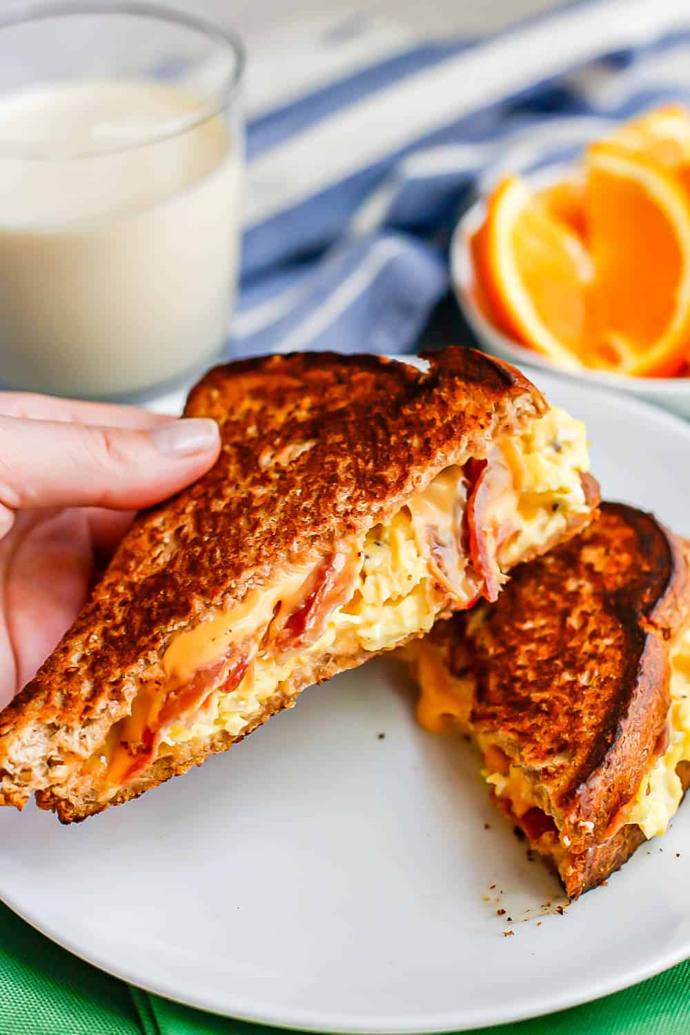 A hand holding a bacon, egg and cheese grilled cheese sandwich