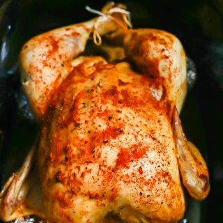 A seasoned and cooked whole chicken in a crock pot