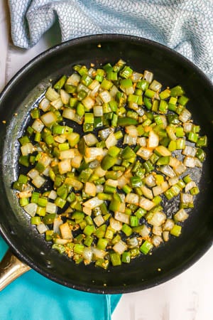 A dark skillet with sautéed onion, green pepper and celery