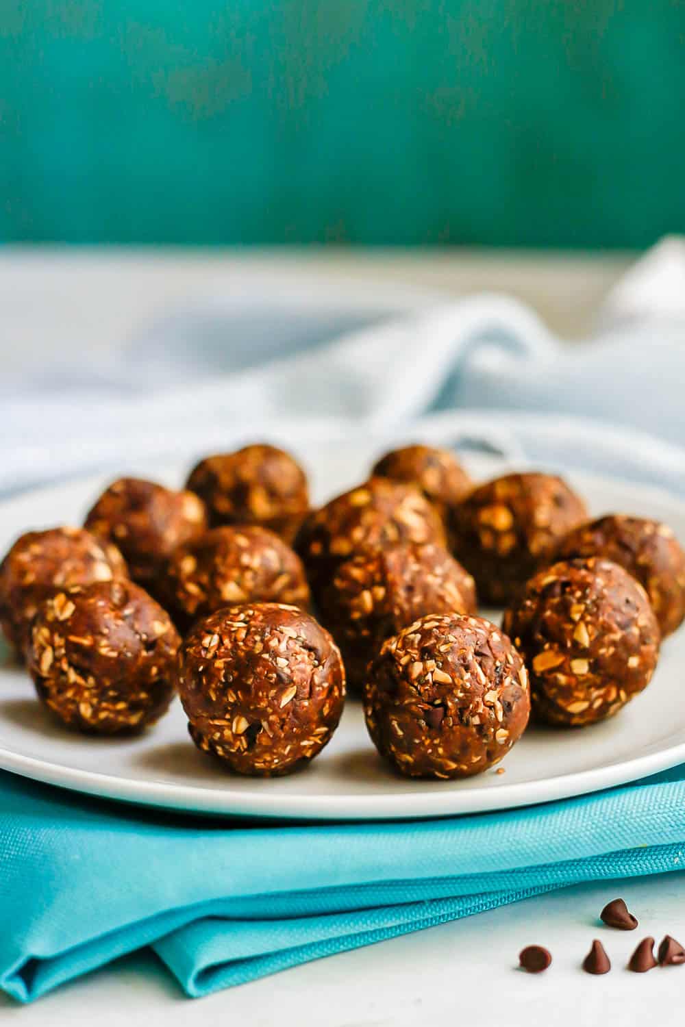 A white plate with chocolate peanut butter energy balls set on teal napkins