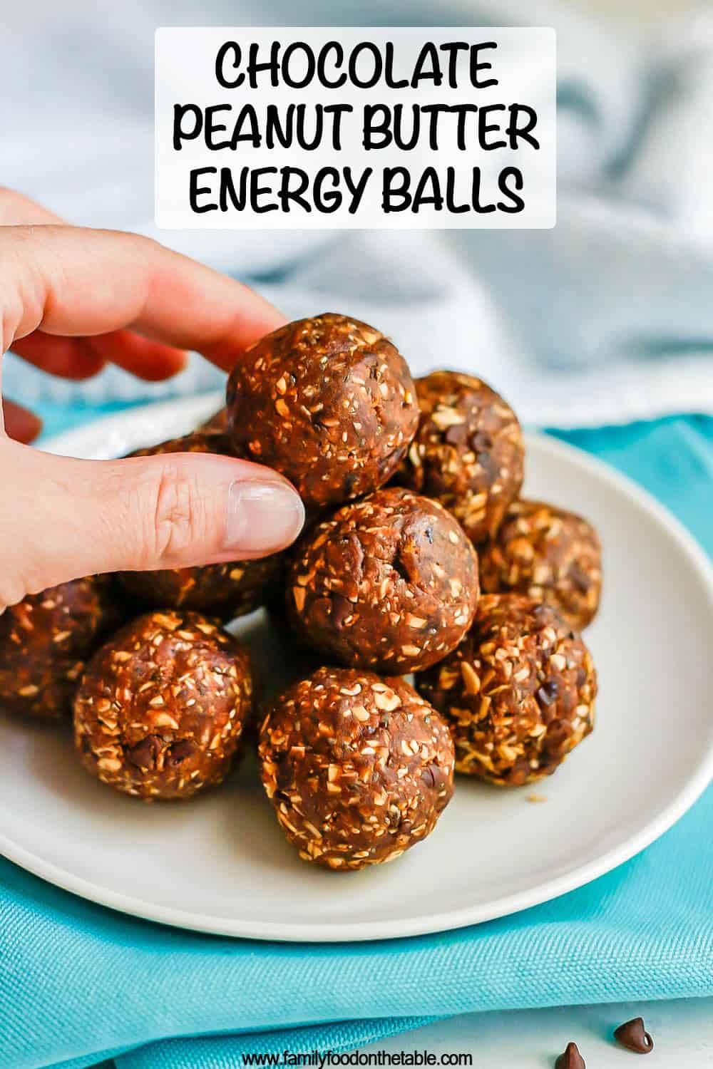 Chocolate peanut butter energy balls piled in a pyramid on a small white plate with a hand reaching for the top one and a text overlay on the photo