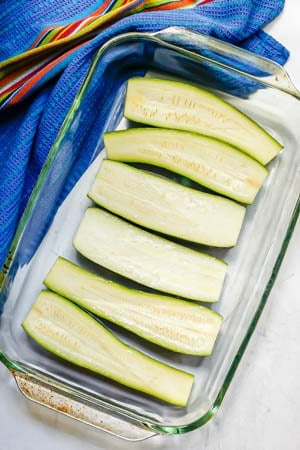 Zucchini halved lengthwise and placed in a glass baking dish