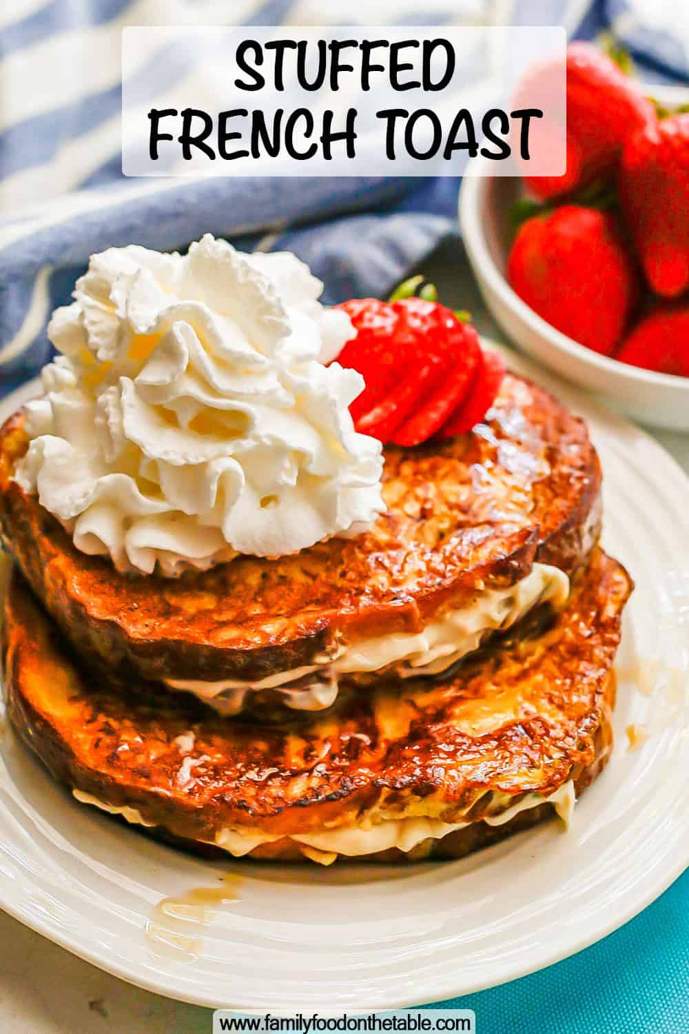 Stuffed French toast on a white plate topped with strawberries and whipped cream and a text overlay on the photo
