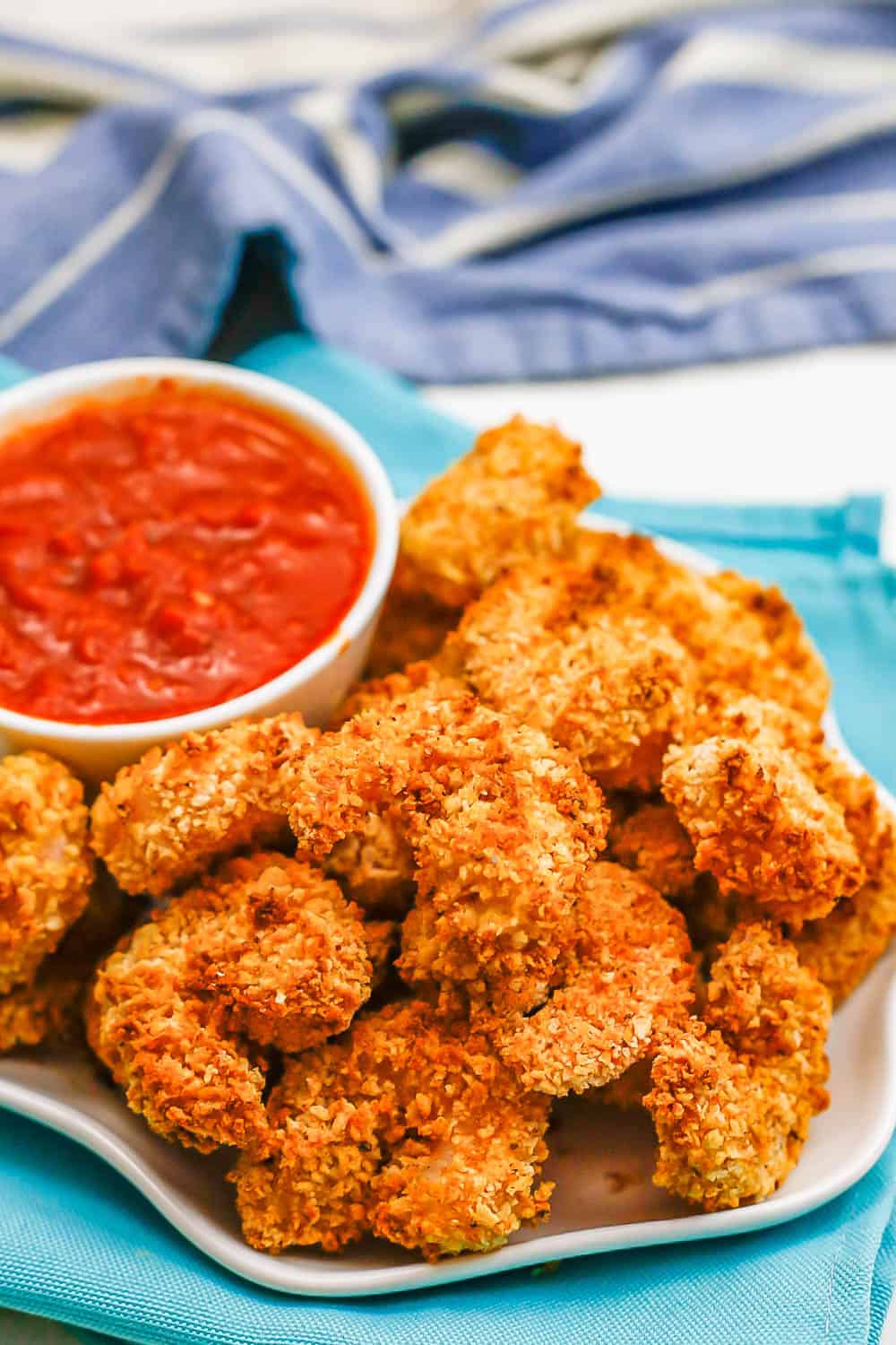 Close up of crispy Air Fryer breaded shrimp served on a white plate with a bowl of marinara