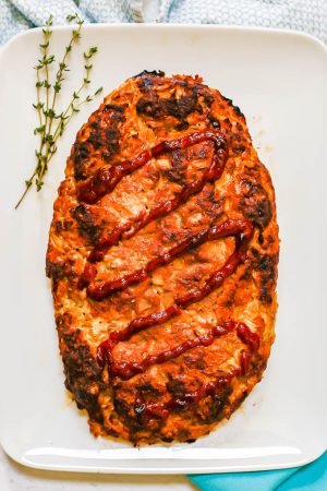 Baked turkey meatloaf served on a rectangular white dish with sprigs of thyme to the side