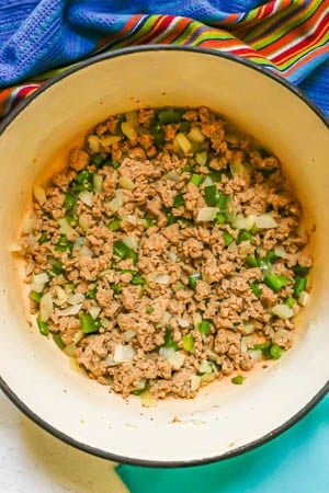 A large Dutch oven with a mixture of cooked ground turkey, green pepper and onion