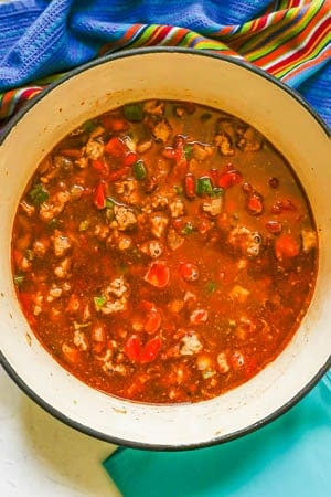 A large Dutch oven with a tomato mixture, ground turkey and vegetables