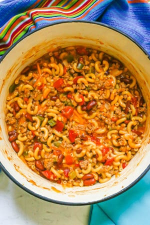 A cheesy ground turkey chili mac with beans and tomatoes being cooked in a large Dutch oven