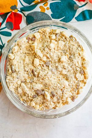 A glass bowl with a crumbly streusel mixture of flour, oats, sugar, butter and pecans