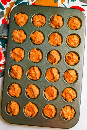 Pumpkin donut batter in a mini muffin tin before being baked