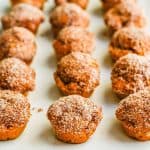 Pumpkin donut holes lined up on a white rectangular plate with teal napkins underneath with a text overlay on the photo