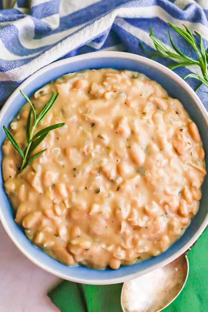 Overhead shot of creamy, slightly mashed cannellini beans in a blue and white bowl