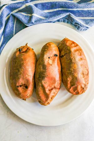 3 oven baked sweet potatoes cooling on a white plate
